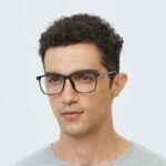 Portrait of a young man wearing glasses in a casual gray t-shirt, looking pensive.